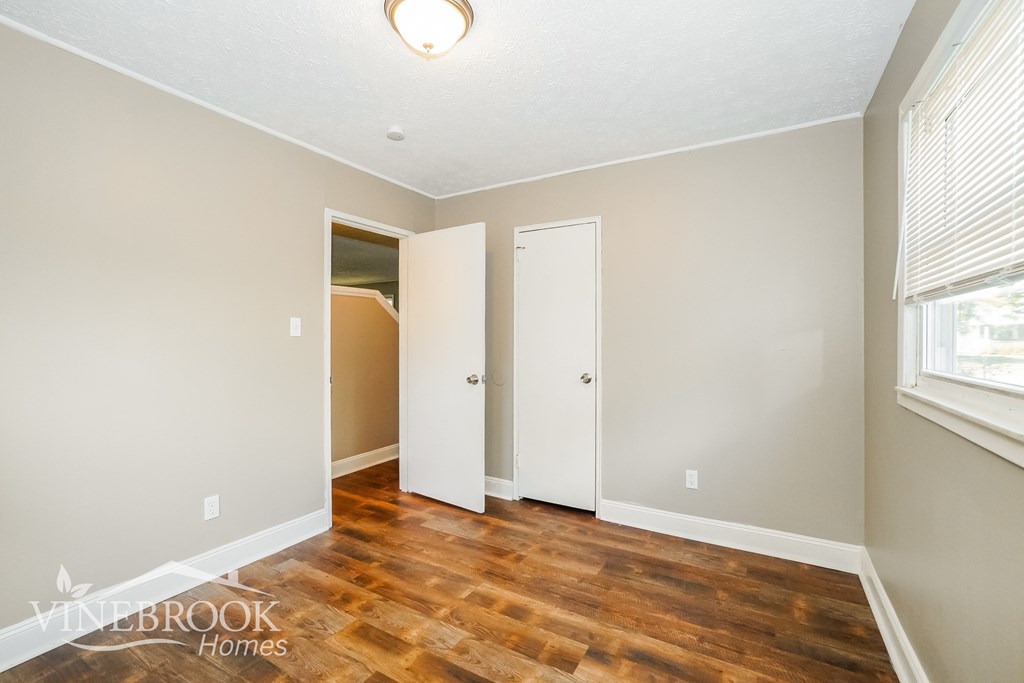 a bedroom with a hard wood floor and a door to a closet