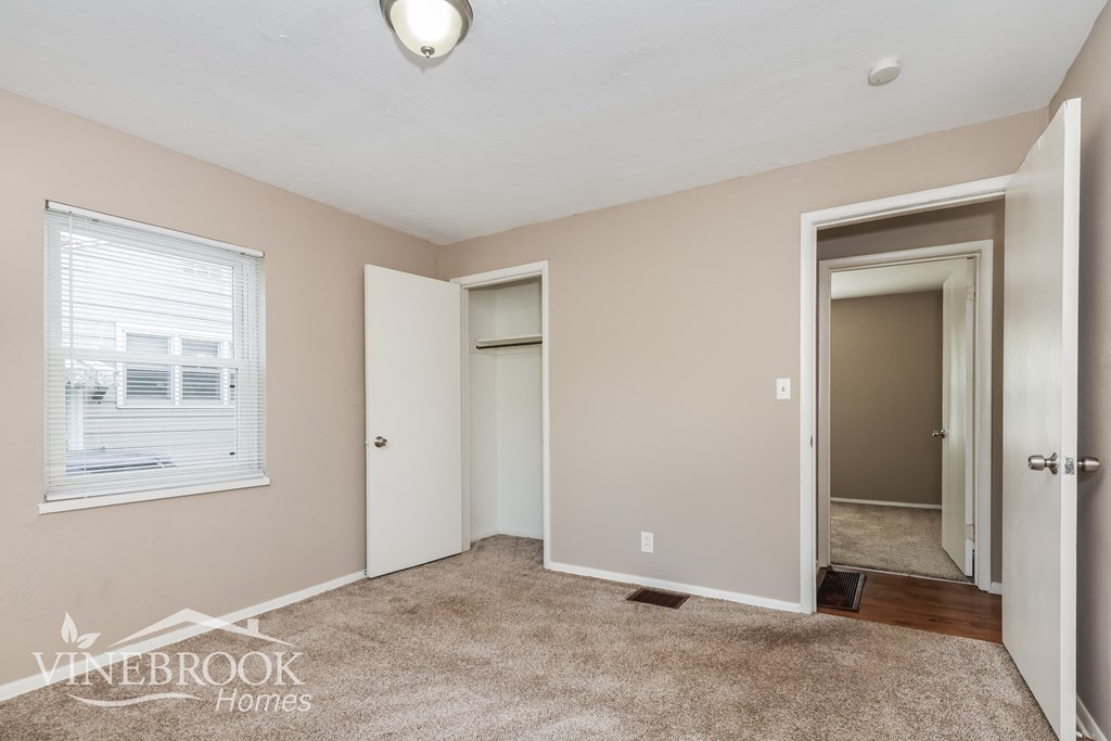 a bedroom with a carpeted floor and a door to a closet