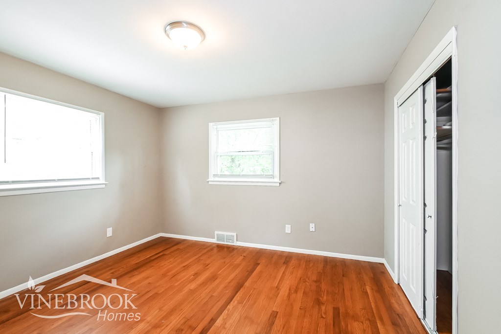a bedroom with a hardwood floor and a closet