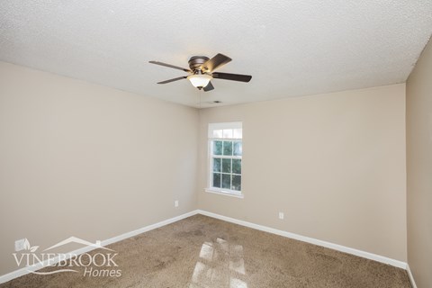 a living room with a ceiling fan and a carpet