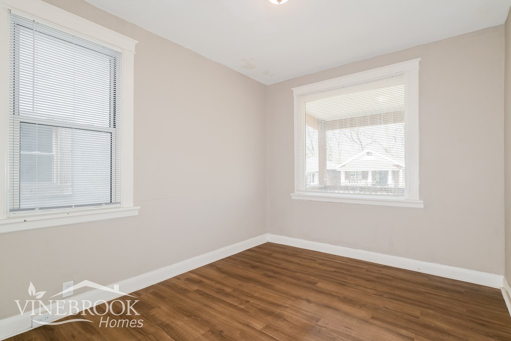 A room with wooden floors and two windows.