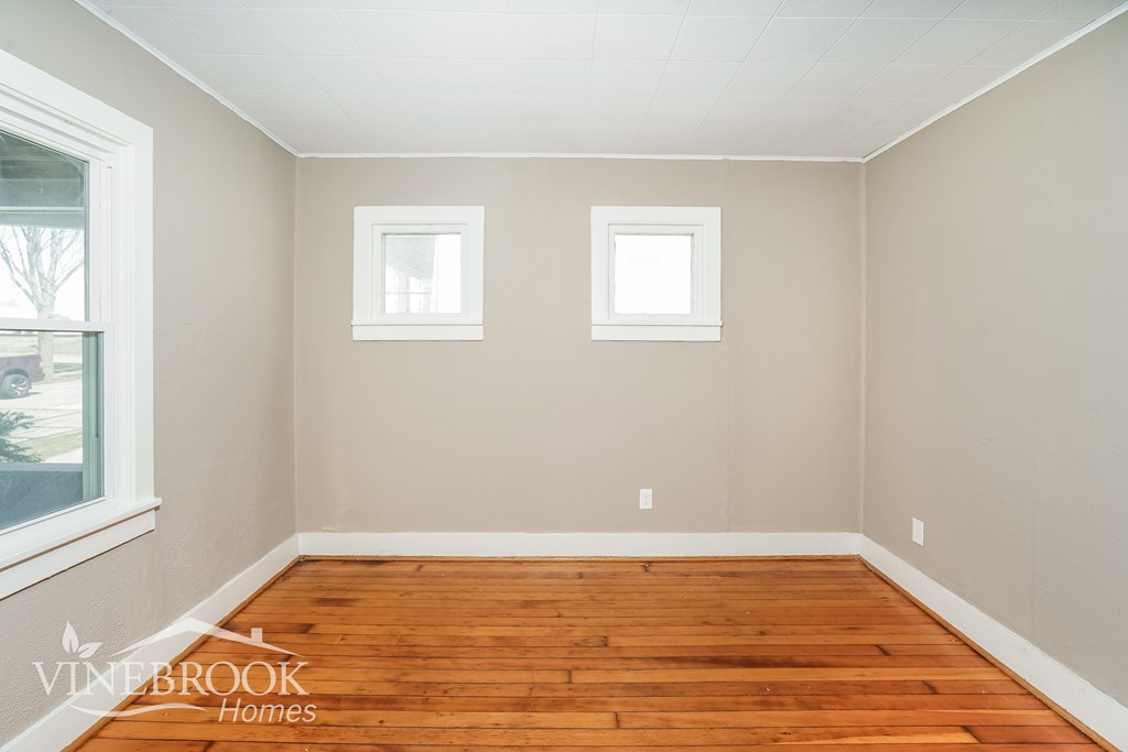 A room with wooden floors and two windows.