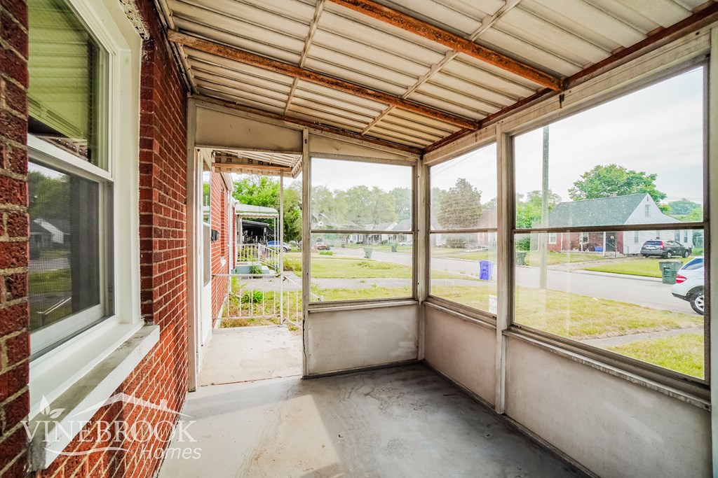 an empty porch with large windows in a brick building
