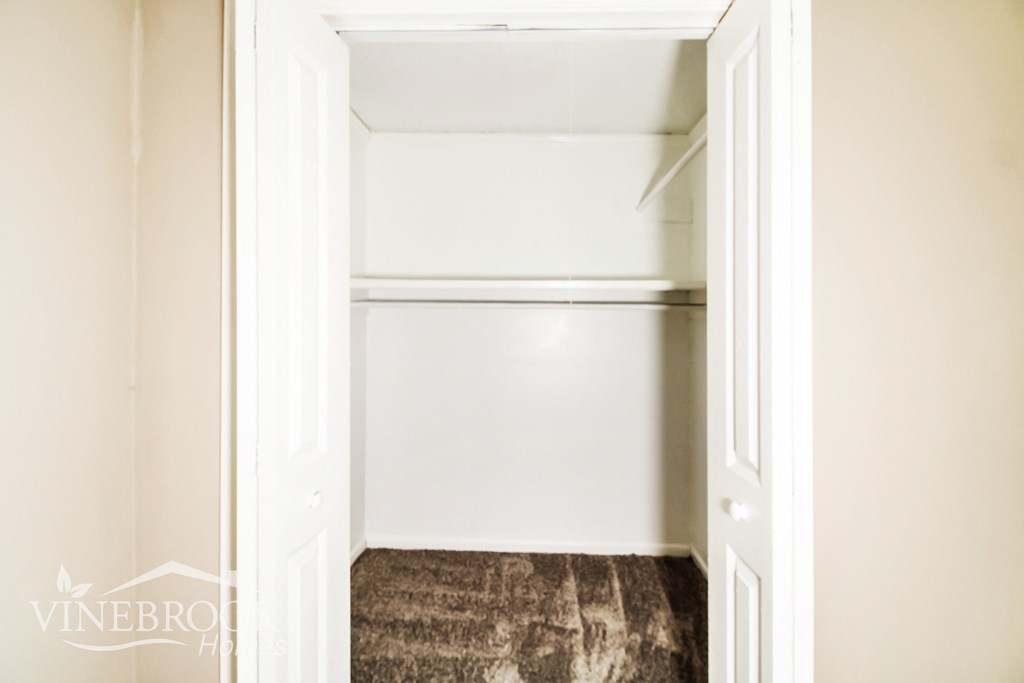 a walk in closet with empty shelves and a carpet
