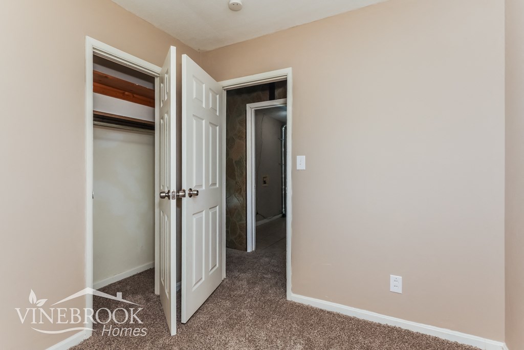 a bedroom with two closets and a hallway with two doors and a door open