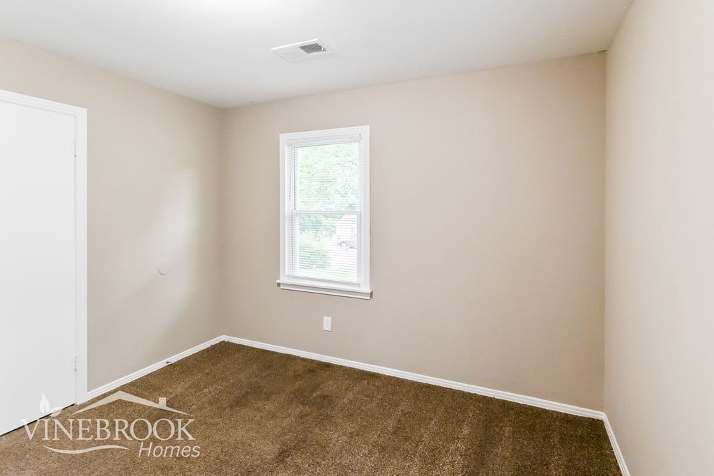 the living room of a home with a brown carpet and a window