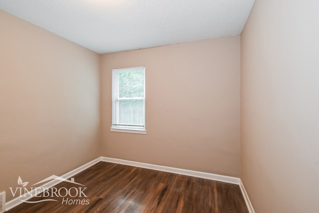 the living room of a home with wooden floors and a window
