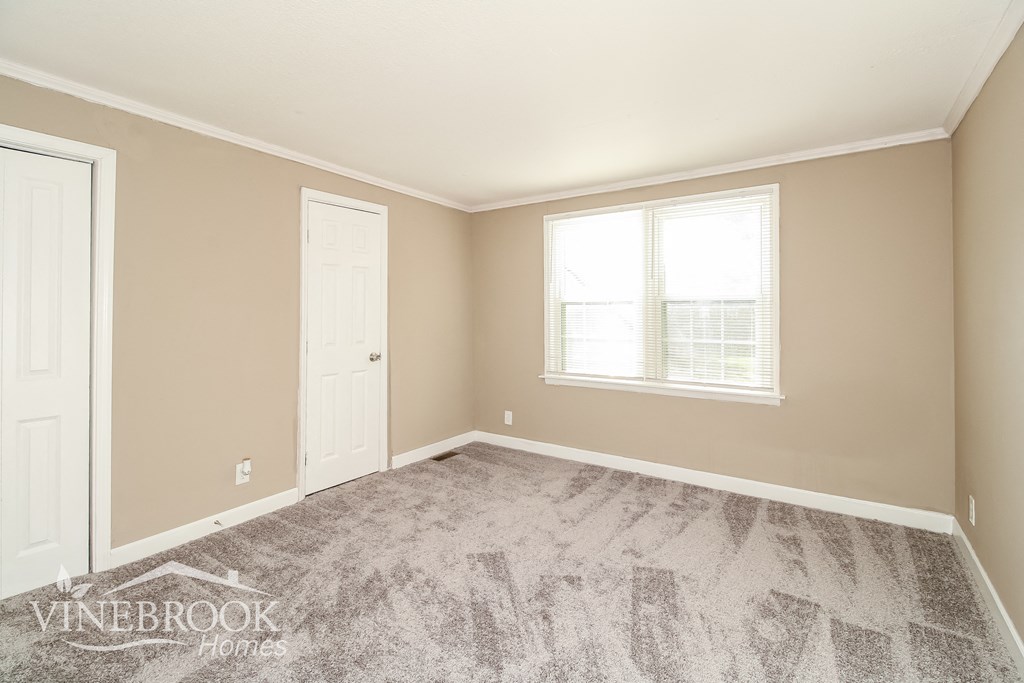 a bedroom with a carpeted floor and a white door and window