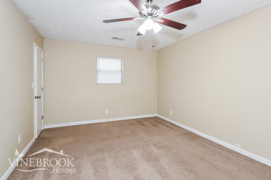 a empty living room with a ceiling fan and carpet