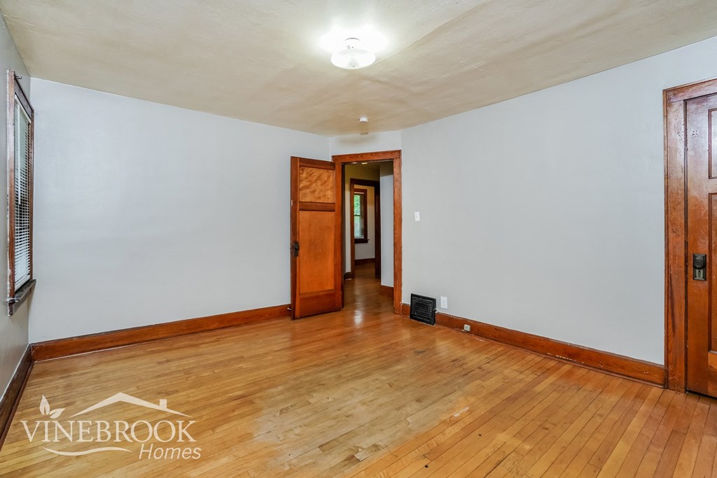 a living room with wood floors and white walls and a door to a hallway