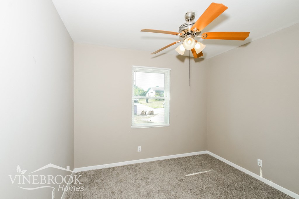 a bedroom with a ceiling fan and a carpet
