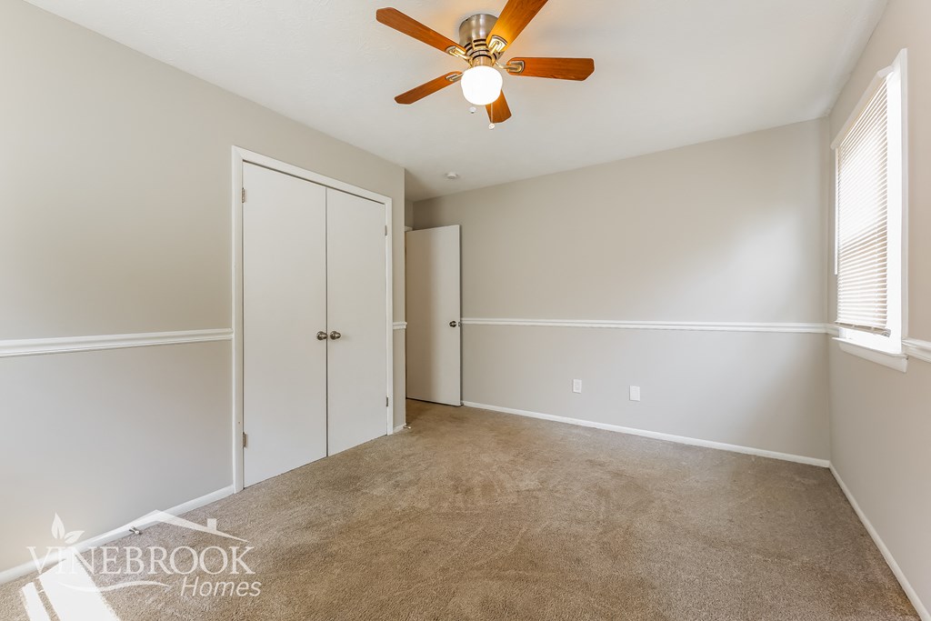 a bedroom with a ceiling fan and a closet