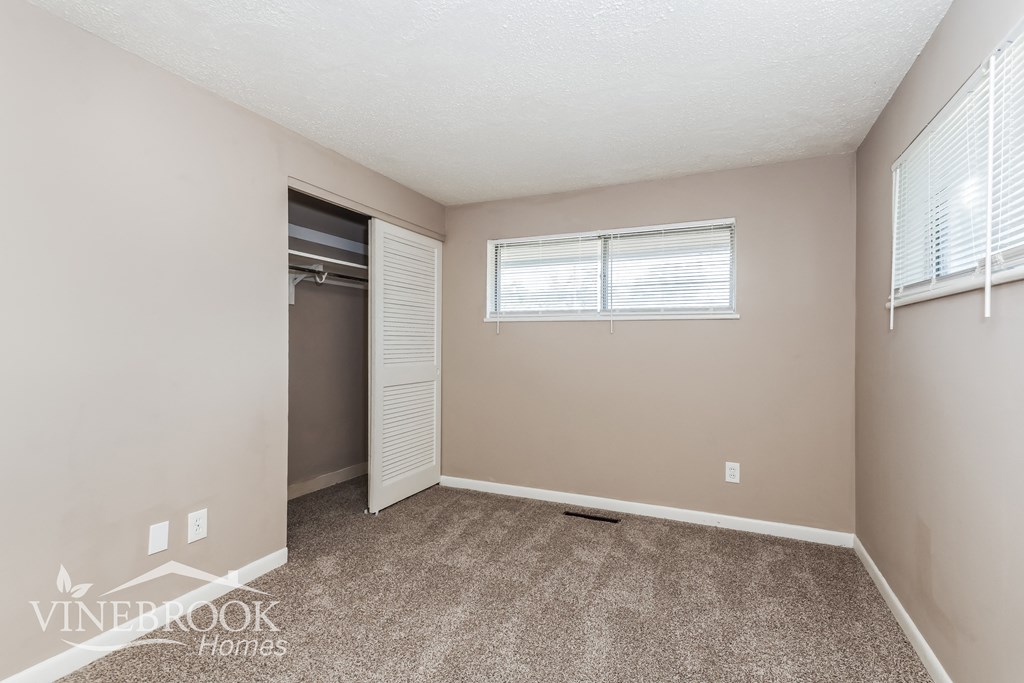 a bedroom with carpet and a closet and a window