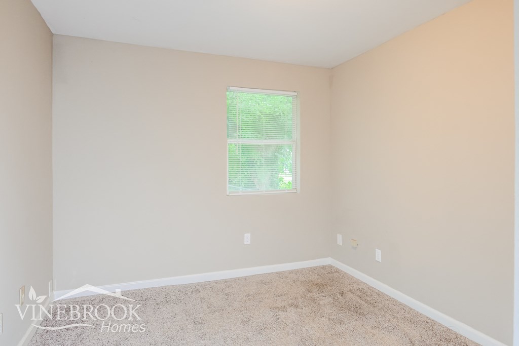 a bedroom with a carpeted floor and a window