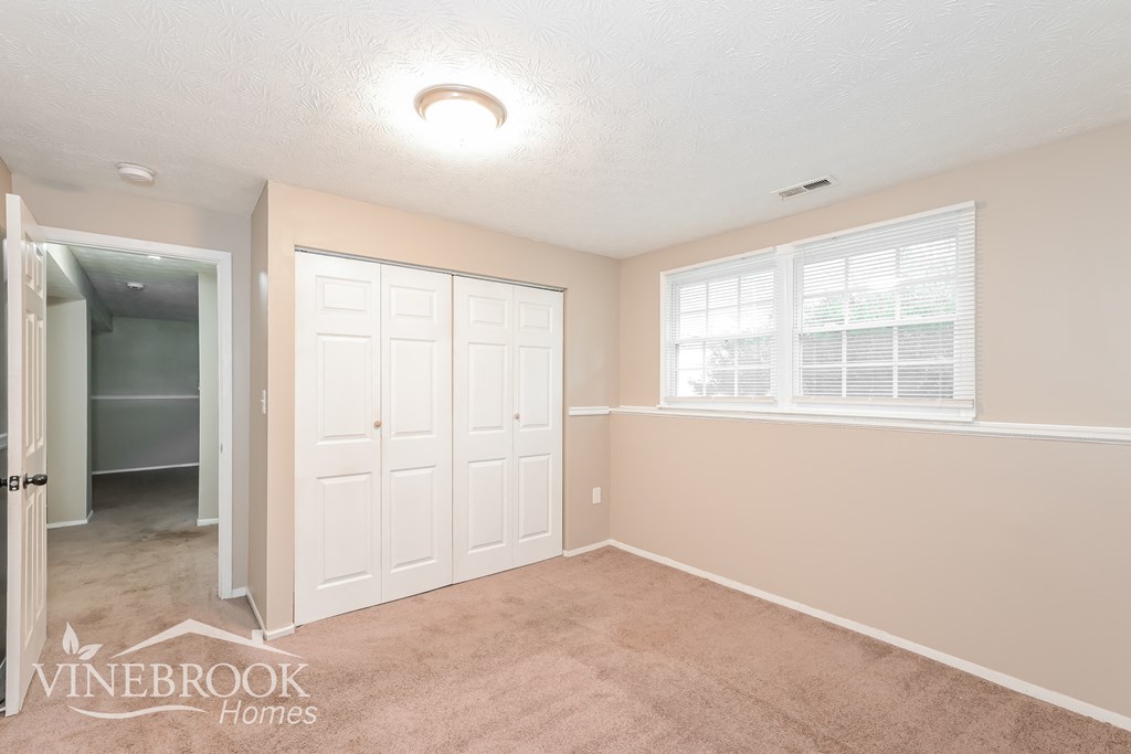 a bedroom with a closet and a white door and a window
