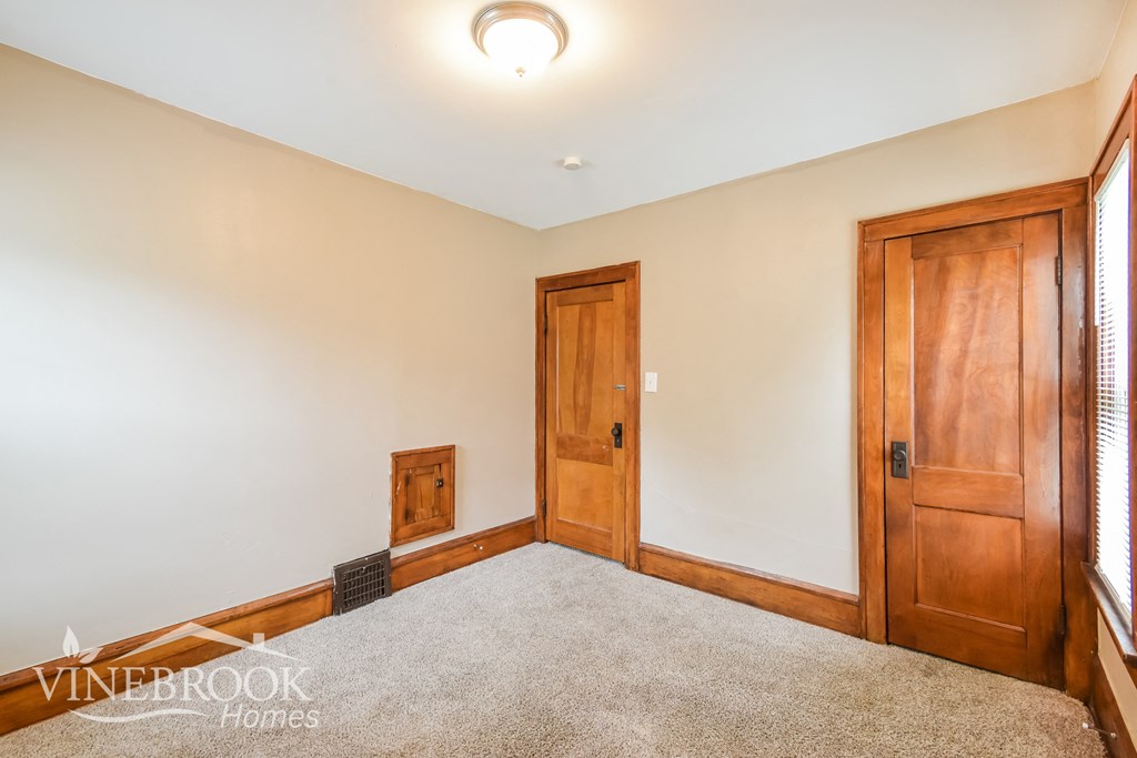 a bedroom with a carpeted floor and two wooden doors