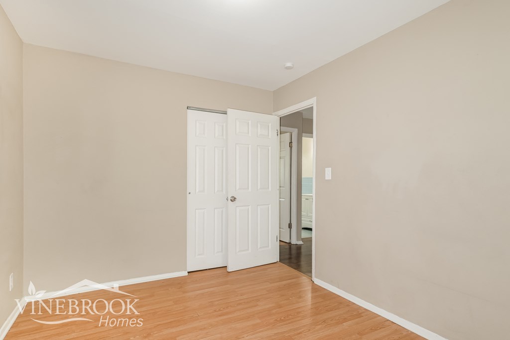 a bedroom with two doors and a hallway with a door to a closet