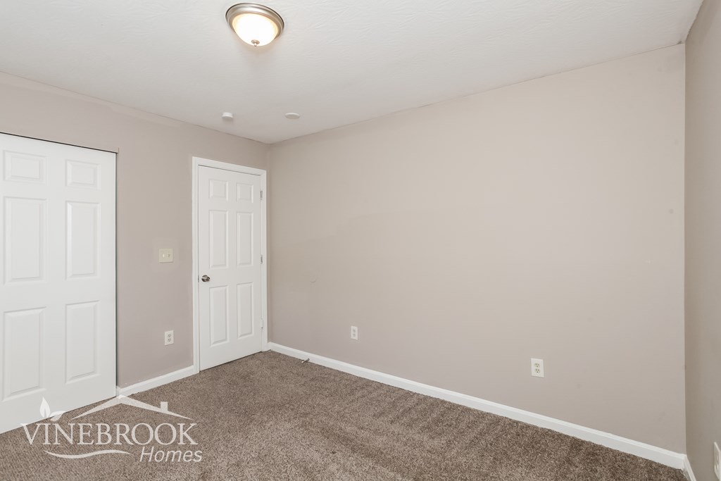 A room with a carpeted floor and a door on the left side.