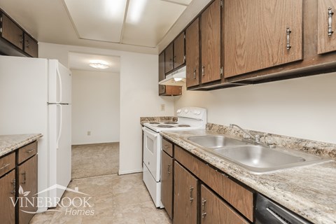 A kitchen with a white refrigerator and brown cabinets.