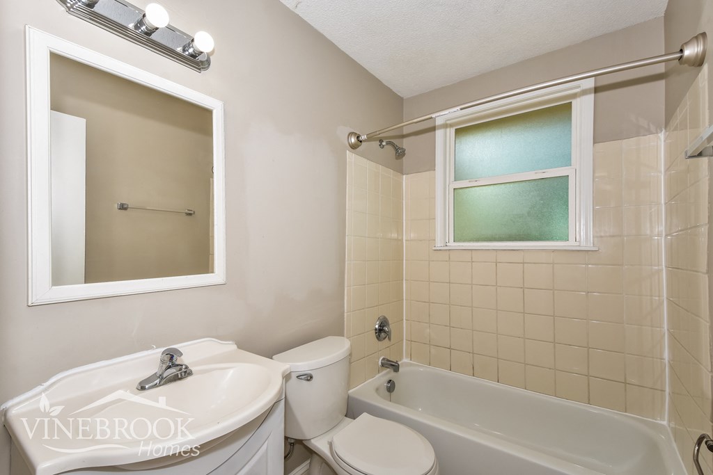 a white bathroom with a tub and a sink and a toilet