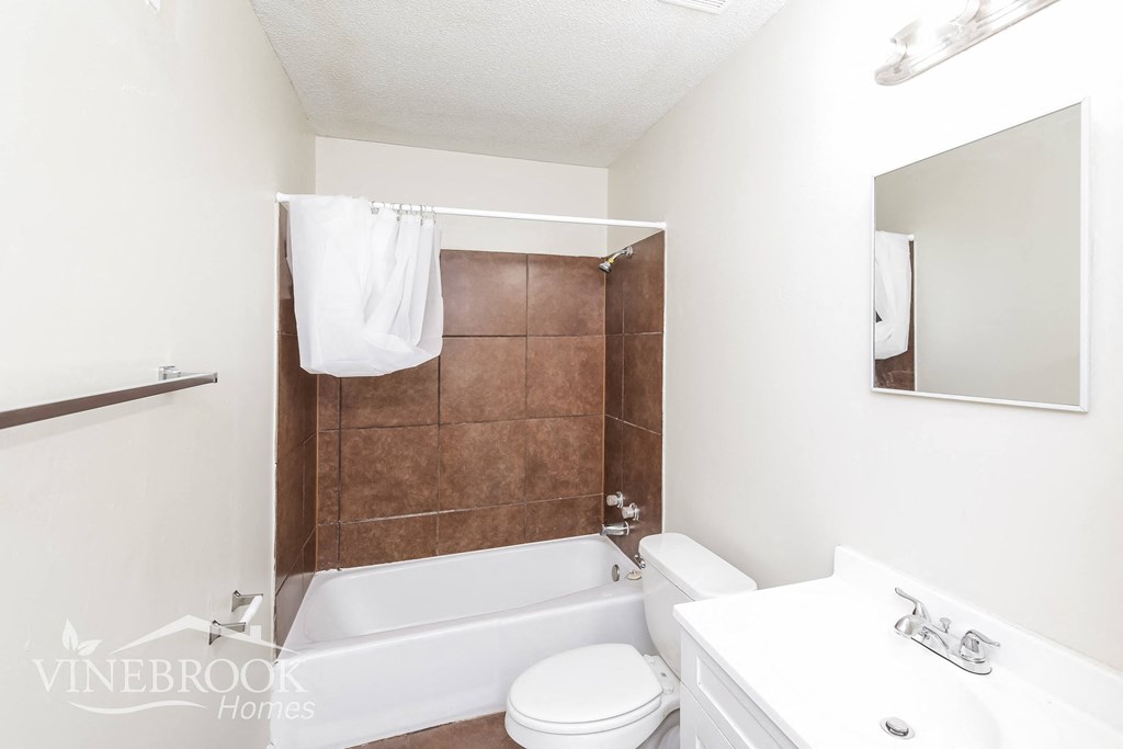 a white bathroom with a tub and a toilet and a sink