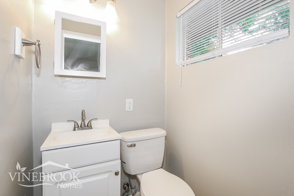 a bathroom with a toilet and a sink and a window
