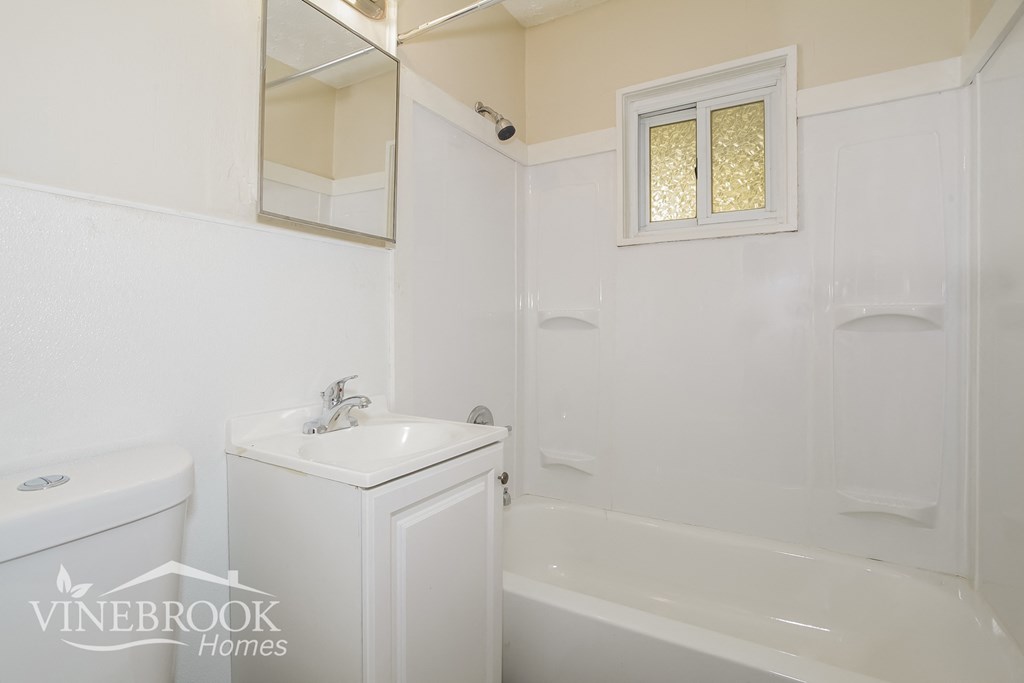 a white bathroom with a sink and a toilet and a tub