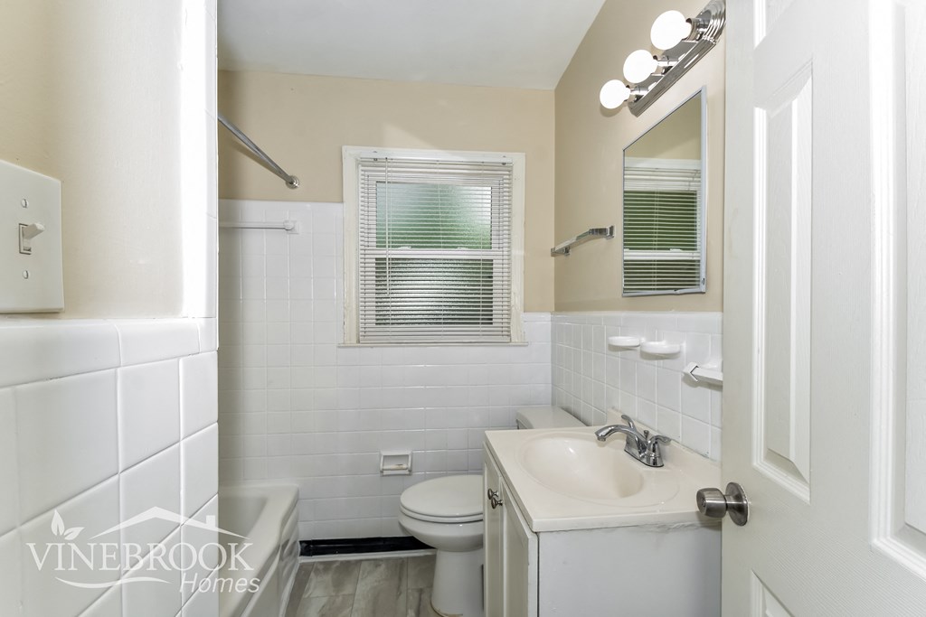a white bathroom with a sink toilet and a mirror
