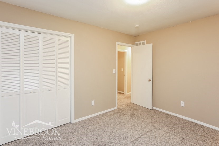 a bedroom with white closet doors and a door to a hallway