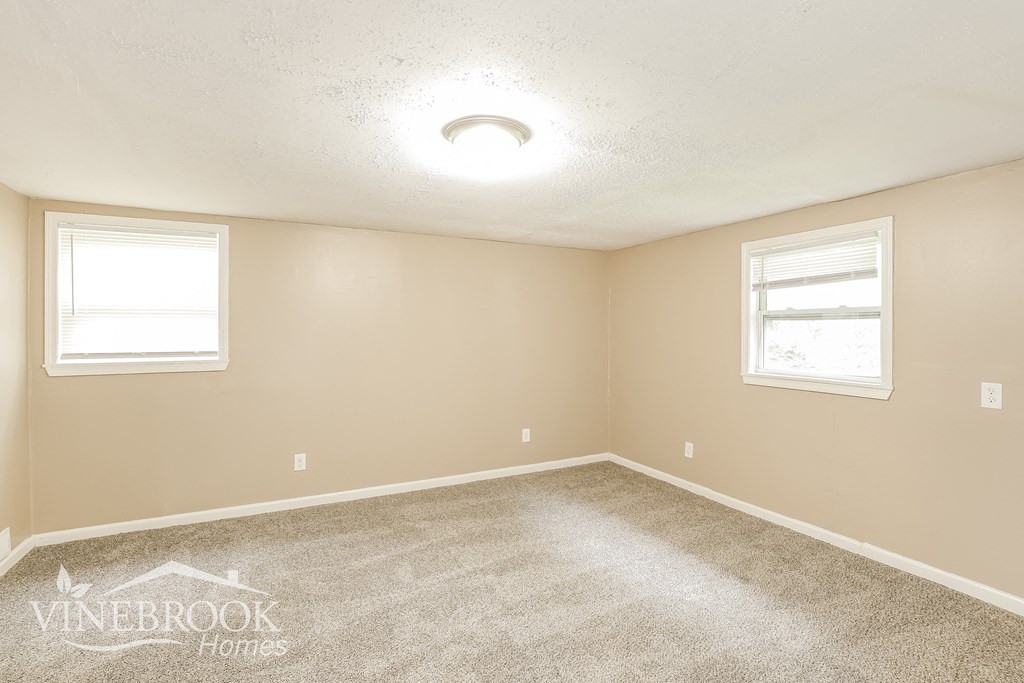 a bedroom with a carpeted floor and two windows