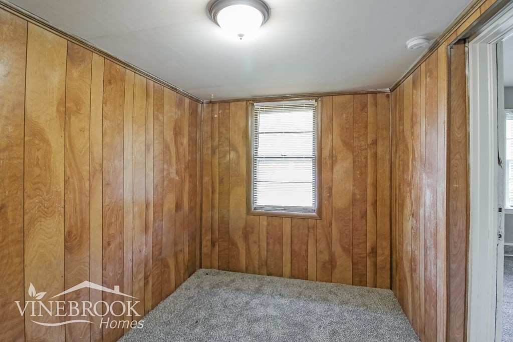 a small room with wood paneling and a window