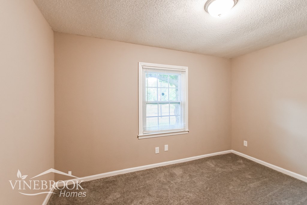 a bedroom with a carpeted floor and a window