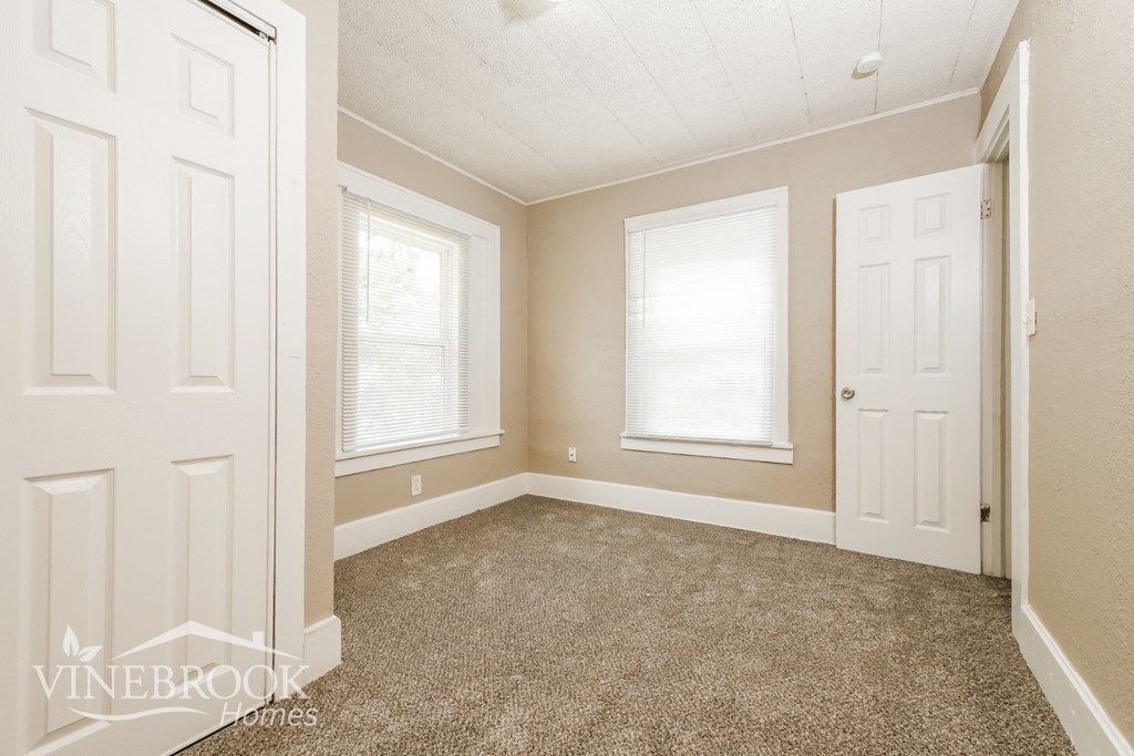 a bedroom with a carpeted floor and two windows