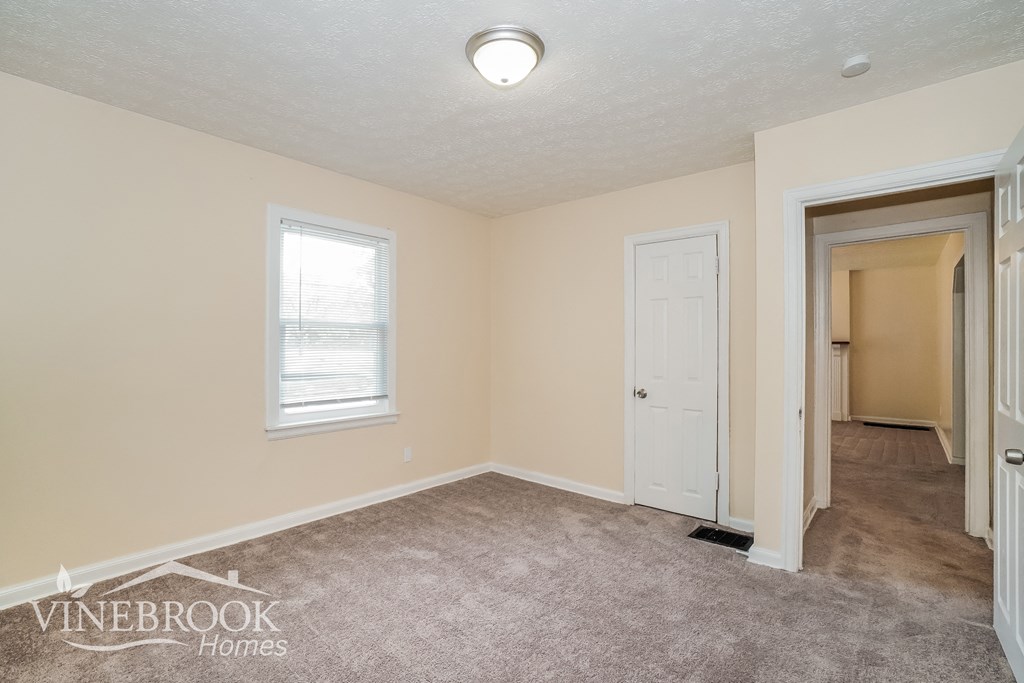 a bedroom with a carpeted floor and a door to a closet