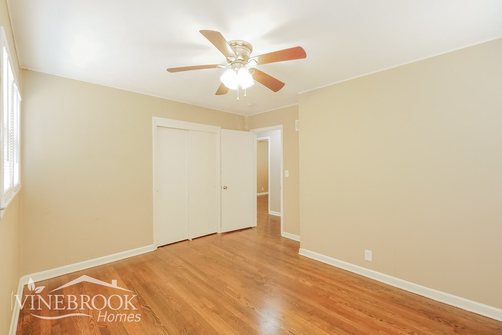 a bedroom with a ceiling fan and wood flooring