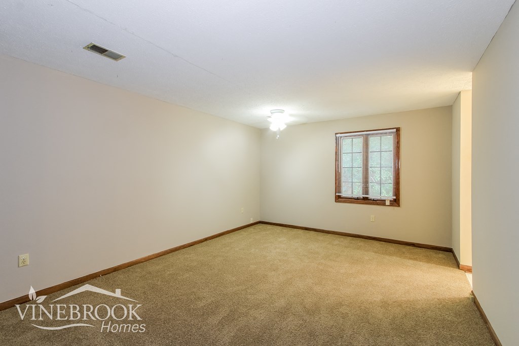 the upstairs living room of a home with carpet and a window