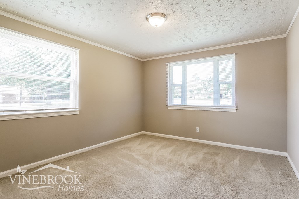 the living room of a home with carpet and two windows