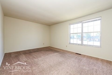 A room with a carpeted floor and a window letting in light.