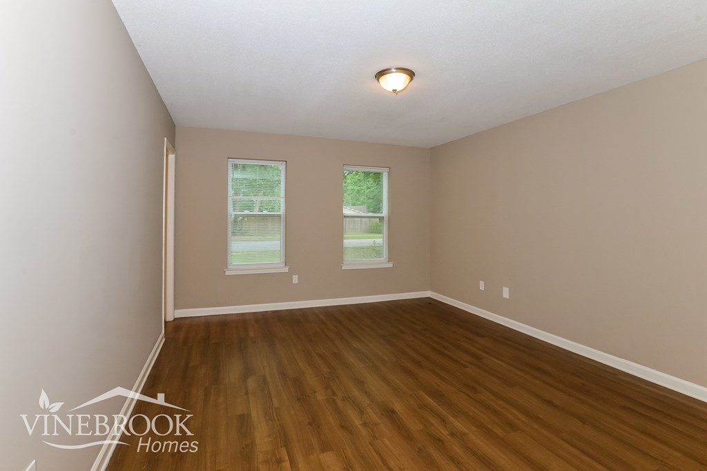 A room with wooden floors and two windows.