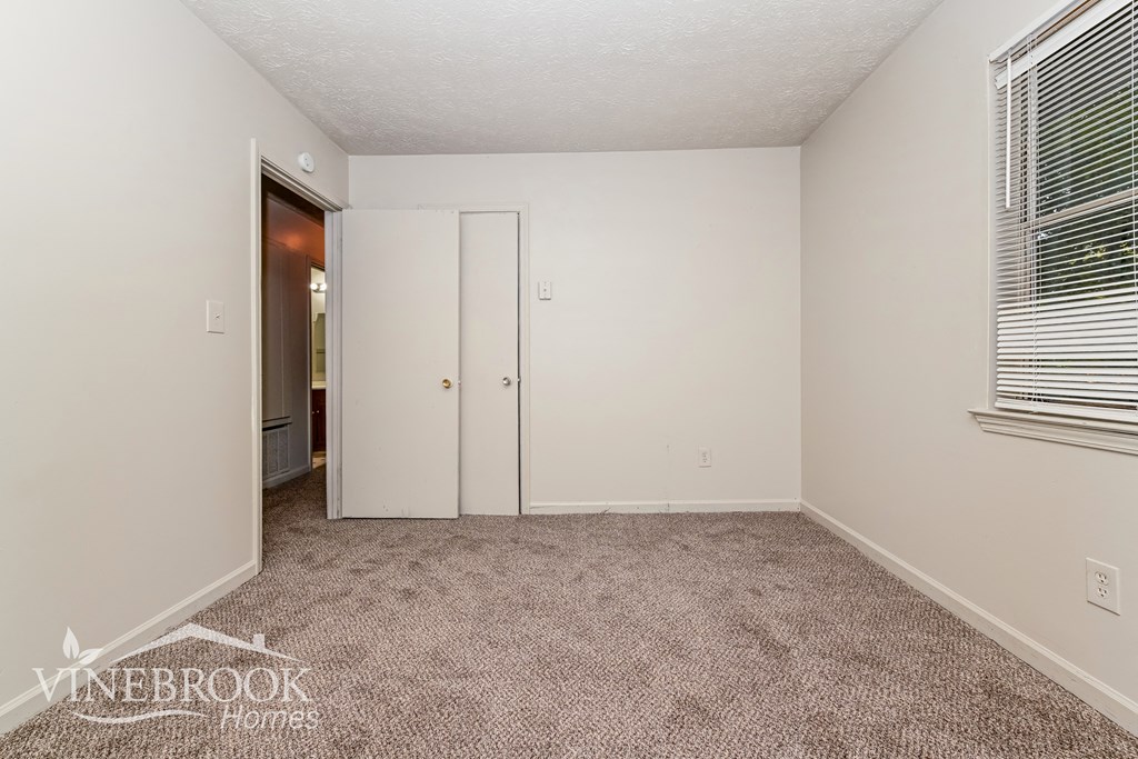 a bedroom with carpet and a door to a closet