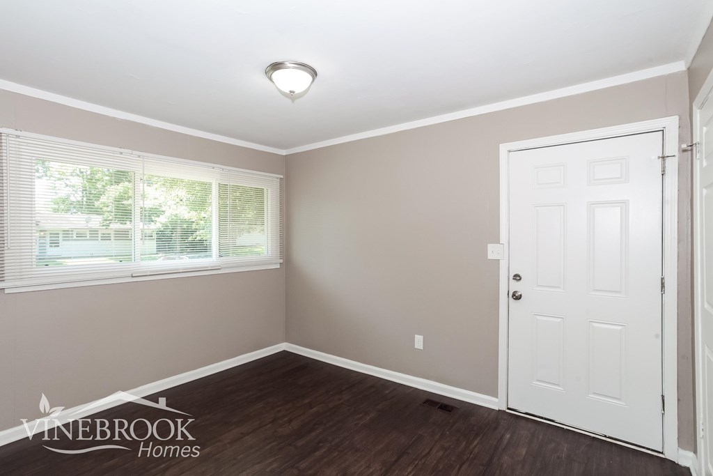A room with a white door and a window with blinds.