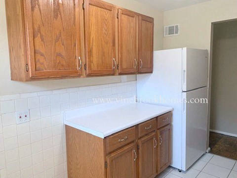 A kitchen with wooden cabinets and a white refrigerator.