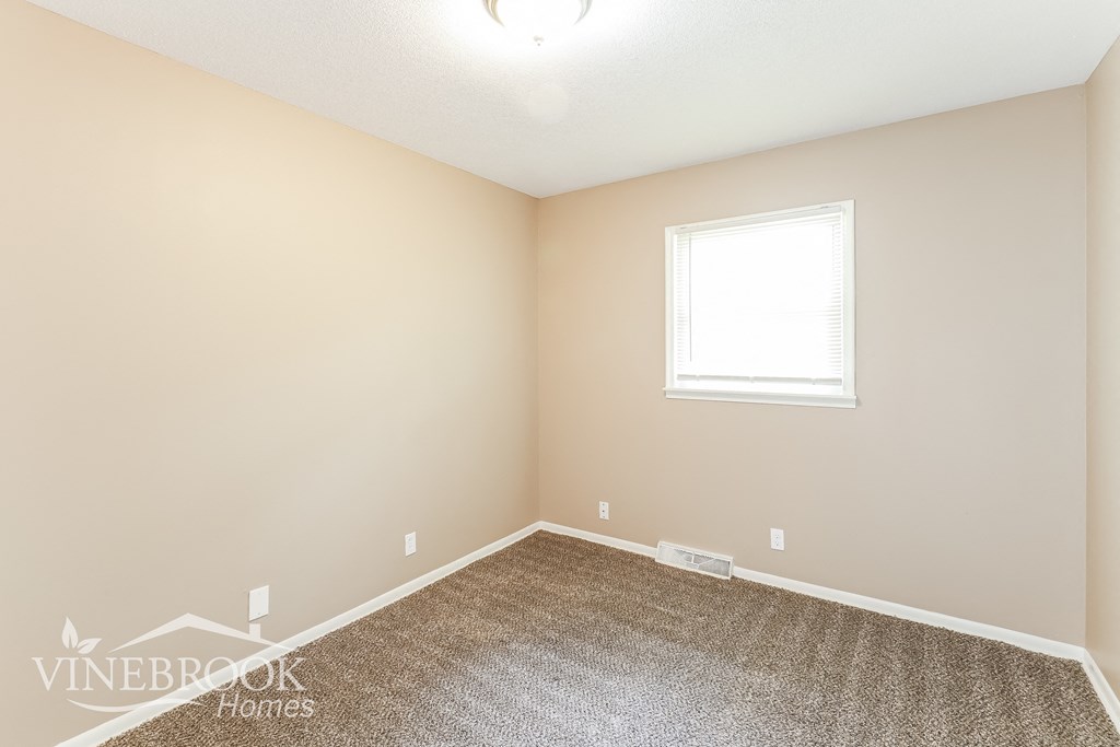 the upstairs bedroom has a carpet and a window