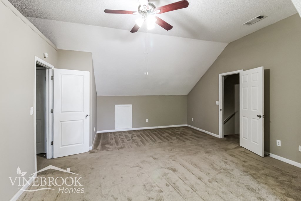 a empty living room with a ceiling fan and white doors