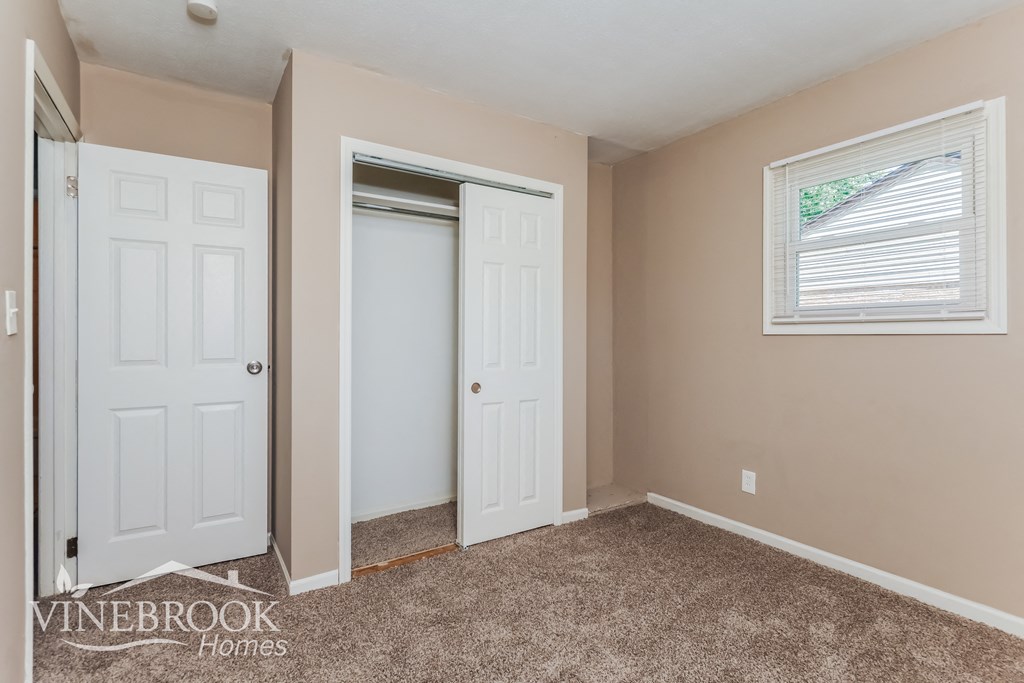 a bedroom with two doors and a closet and a window