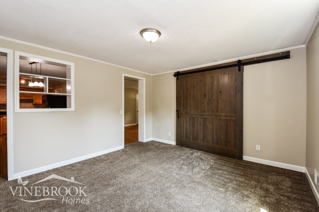 a living room with a door to a hallway and a carpeted floor