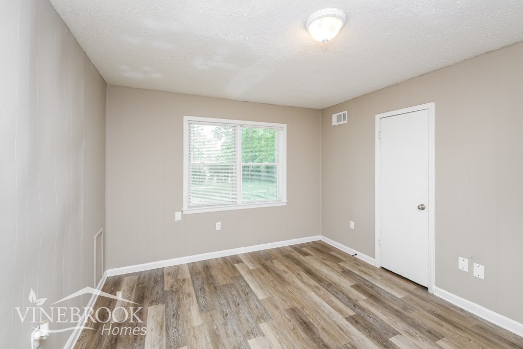 a bedroom with a hardwood floor and a white door