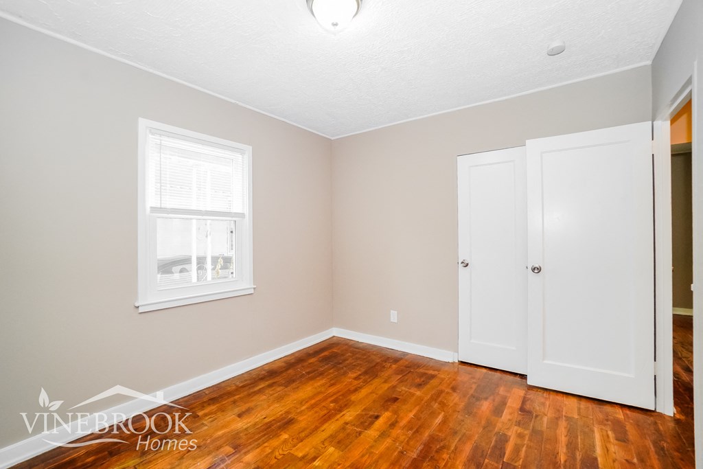 a bedroom with a hard wood floor and two white doors