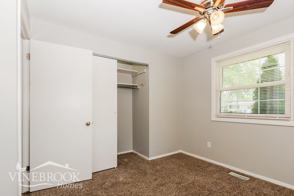 a bedroom with a closet and a ceiling fan