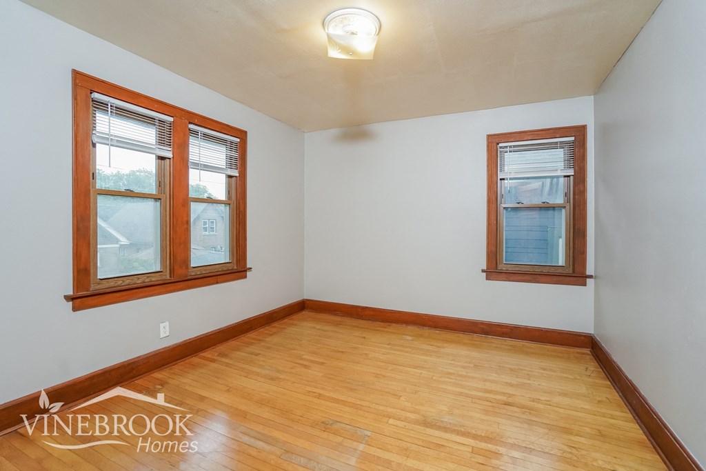 the living room of a home with wood flooring and two windows